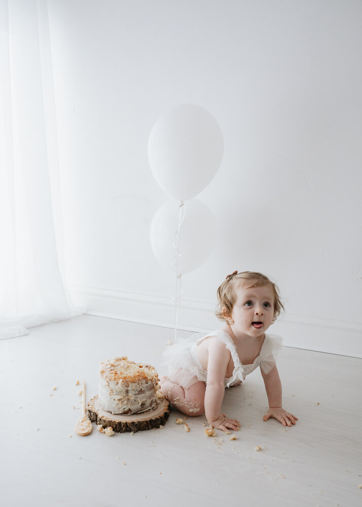 Baby girl first birthday cake and balloons
