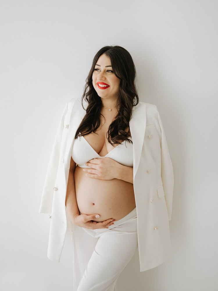 Pregnant woman holding her baby bump and looking to the side during a maternity photography session in Reigate