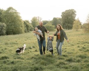 Family walking together in a green park during a relaxed outdoor photography session with their children and dog.
