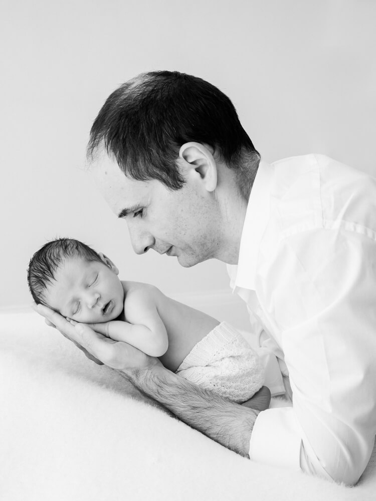 Father gently bonding with his newborn baby during a natural newborn photography session in Epsom